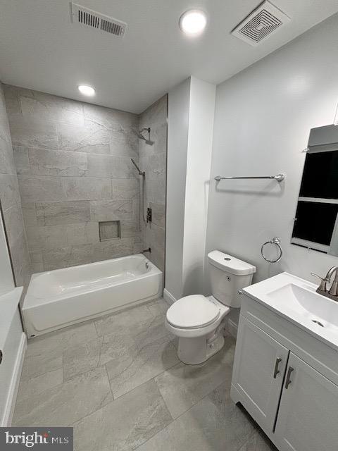 full bathroom featuring vanity, tiled shower / bath combo, and toilet