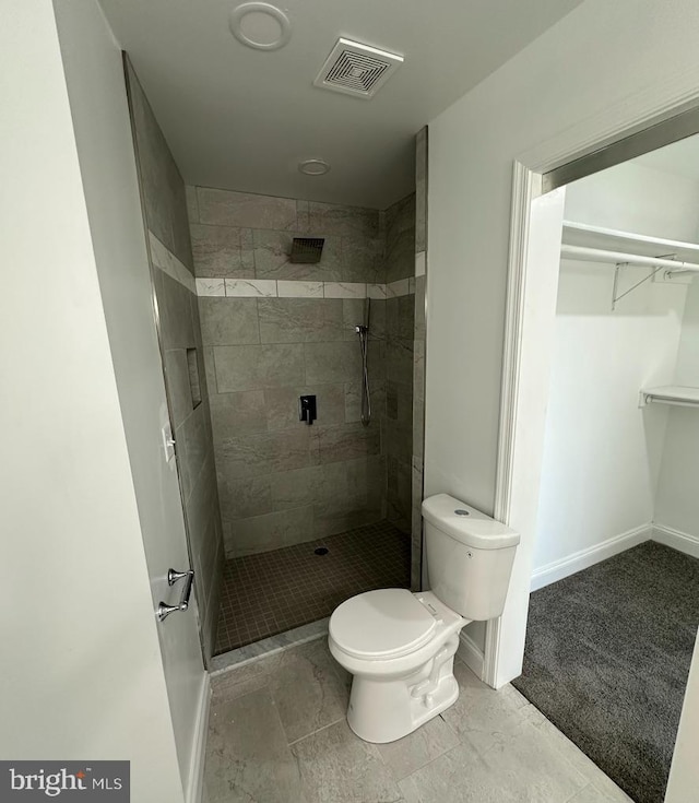 bathroom with a tile shower and toilet