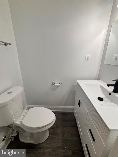 bathroom with hardwood / wood-style flooring, vanity, and toilet