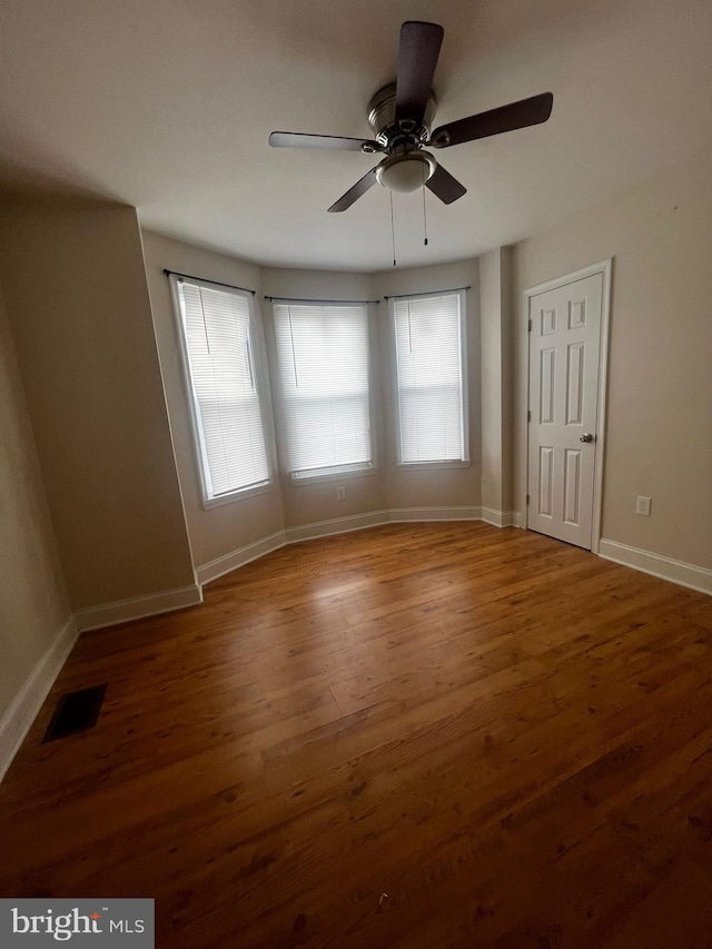 empty room with ceiling fan, a healthy amount of sunlight, and wood-type flooring