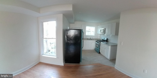 kitchen featuring tasteful backsplash, appliances with stainless steel finishes, white cabinets, and light wood-type flooring