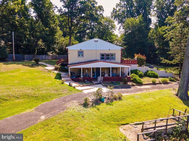 rear view of house featuring covered porch and a lawn