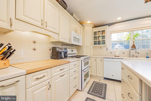 kitchen with light tile patterned floors, white appliances, and decorative backsplash