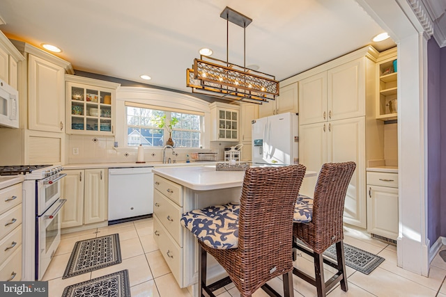 kitchen featuring sink, white appliances, light tile patterned floors, hanging light fixtures, and a kitchen island