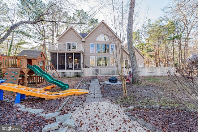 rear view of property featuring a sunroom and a playground