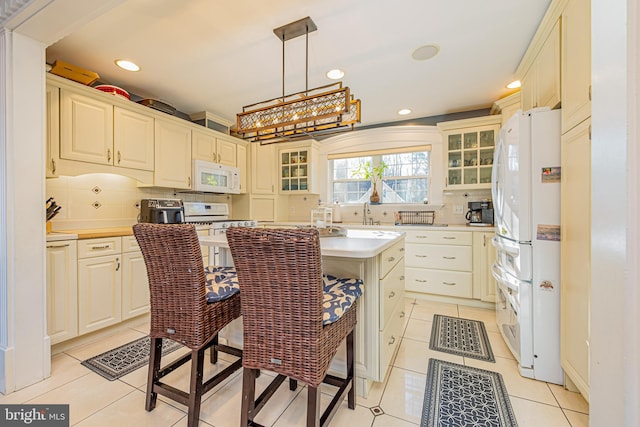 kitchen with tasteful backsplash, hanging light fixtures, a center island, light tile patterned floors, and white appliances