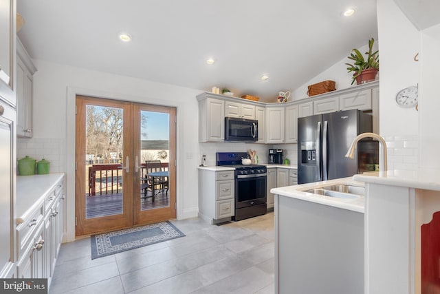 kitchen featuring a sink, vaulted ceiling, light countertops, appliances with stainless steel finishes, and french doors