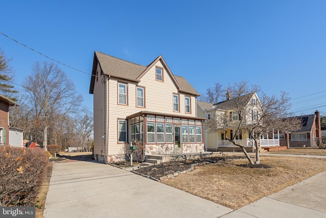 traditional-style house with a sunroom and roof with shingles