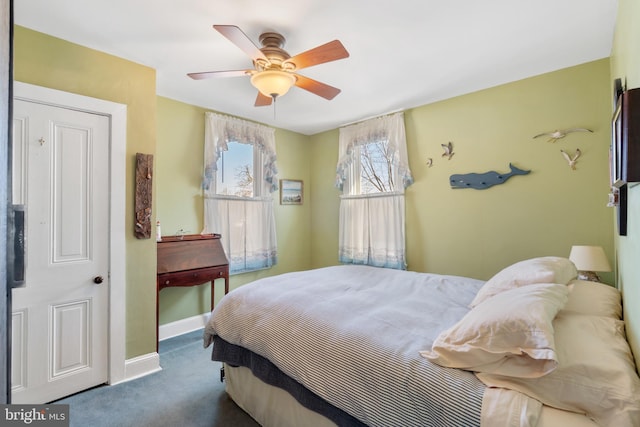 bedroom with ceiling fan, dark carpet, and baseboards