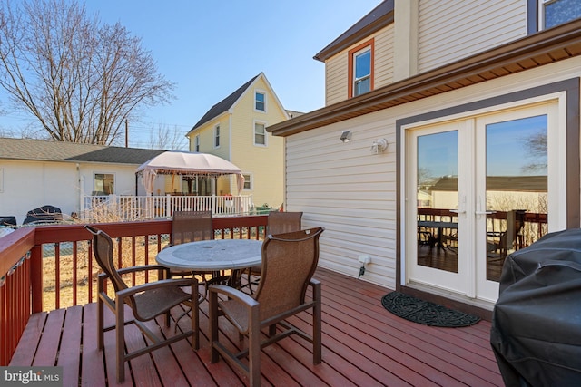 deck with outdoor dining area, french doors, grilling area, and a gazebo