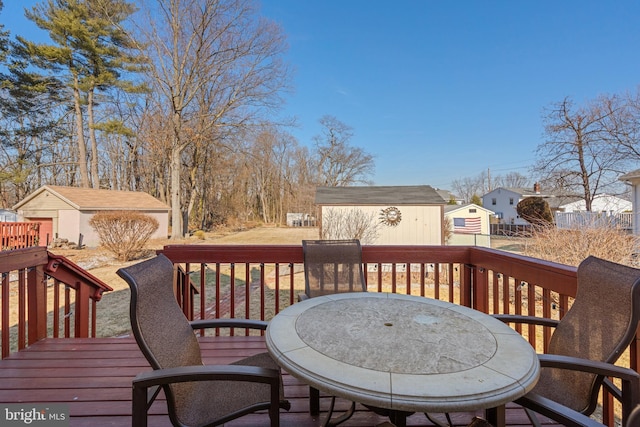 wooden terrace featuring outdoor dining area, an outdoor structure, and a storage unit