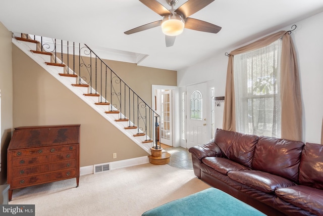 carpeted living area featuring a ceiling fan, visible vents, stairway, and baseboards