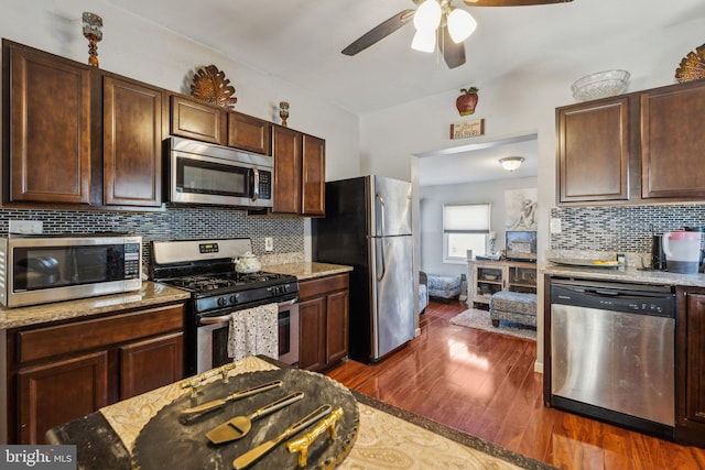 kitchen featuring stainless steel appliances, dark hardwood / wood-style flooring, dark brown cabinets, light stone counters, and decorative backsplash