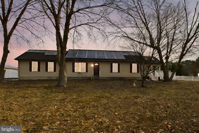 view of front of home with a lawn and solar panels