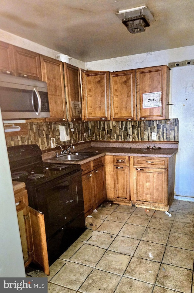 kitchen featuring electric range, stainless steel microwave, a sink, and brown cabinetry