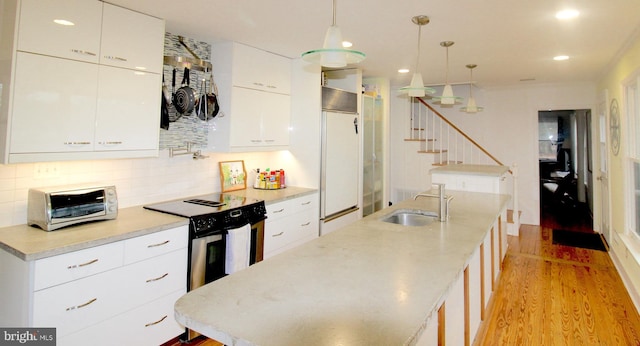 kitchen with sink, tasteful backsplash, decorative light fixtures, electric stove, and white cabinets