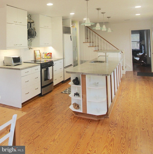 kitchen featuring white cabinetry, hanging light fixtures, stainless steel electric stove, and light hardwood / wood-style floors