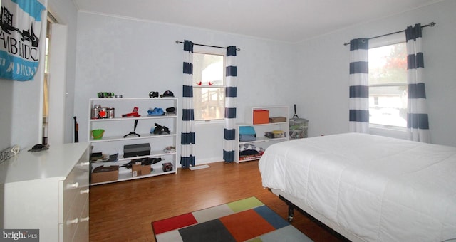 bedroom featuring ornamental molding, dark hardwood / wood-style flooring, and multiple windows