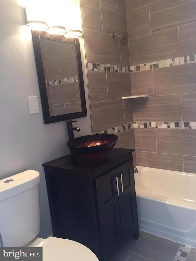 full bathroom with tiled shower / bath combo, vanity, tile patterned floors, and toilet