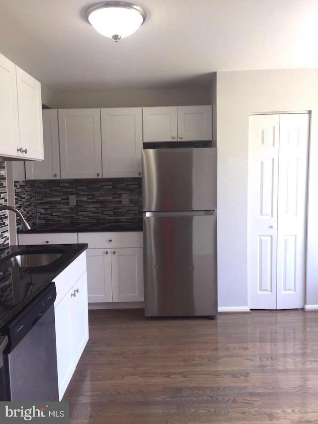 kitchen featuring white cabinetry, sink, dark hardwood / wood-style flooring, decorative backsplash, and stainless steel appliances