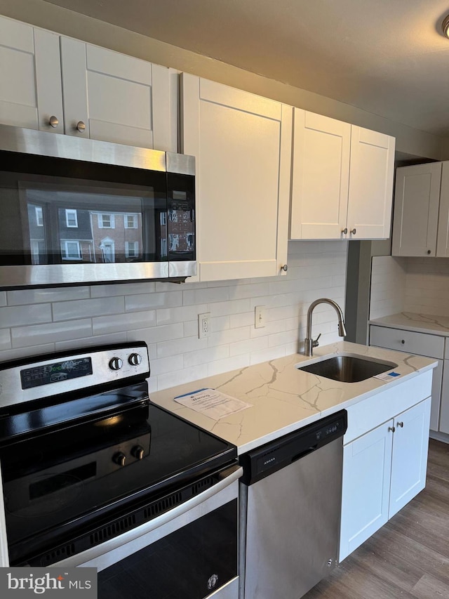 kitchen with stainless steel appliances, sink, decorative backsplash, and white cabinets