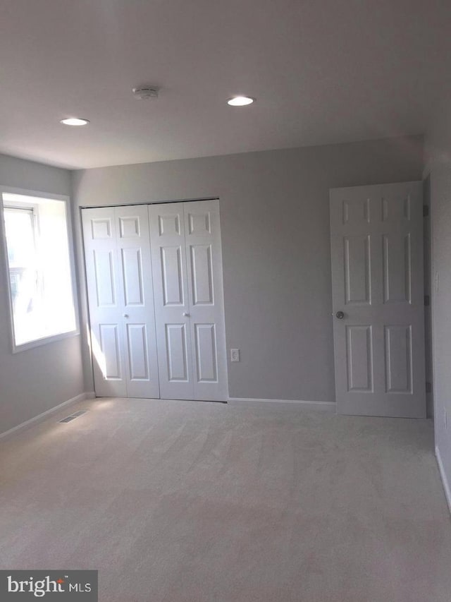 unfurnished bedroom featuring light colored carpet and a closet