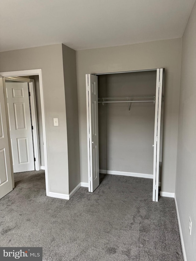 unfurnished bedroom featuring a closet and dark colored carpet