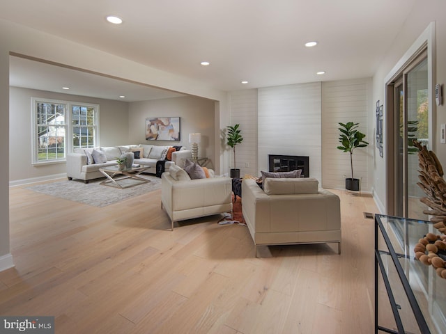 living room featuring recessed lighting, baseboards, a fireplace, and light wood finished floors