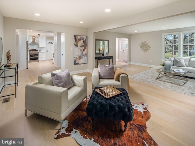 living room featuring light wood-type flooring, baseboards, and recessed lighting