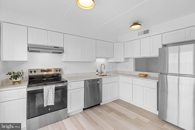 128 Roberts Ln Unit 301, Alexandria, VA 22314 - kitchen with stainless steel appliances, under cabinet range hood, a sink, white cabinetry, and light countertops