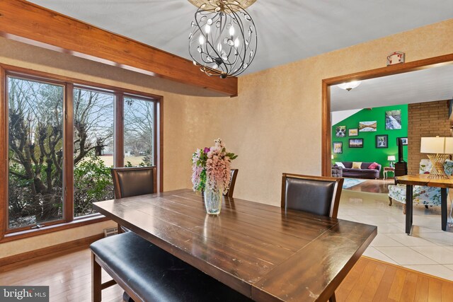 dining space with beam ceiling, light hardwood / wood-style floors, and a notable chandelier