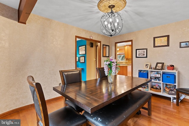 dining space featuring beamed ceiling, an inviting chandelier, and wood-type flooring