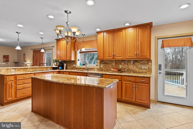 kitchen featuring hanging light fixtures, stainless steel dishwasher, a center island, sink, and kitchen peninsula