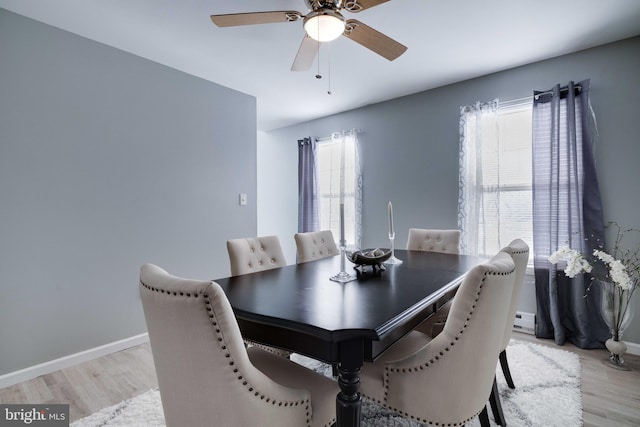 dining space featuring baseboard heating, ceiling fan, and light wood-type flooring