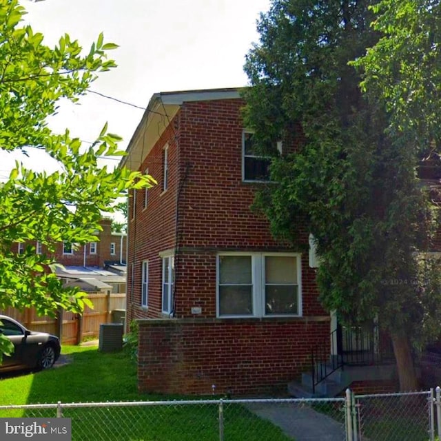 view of side of property with a yard, brick siding, and a fenced front yard