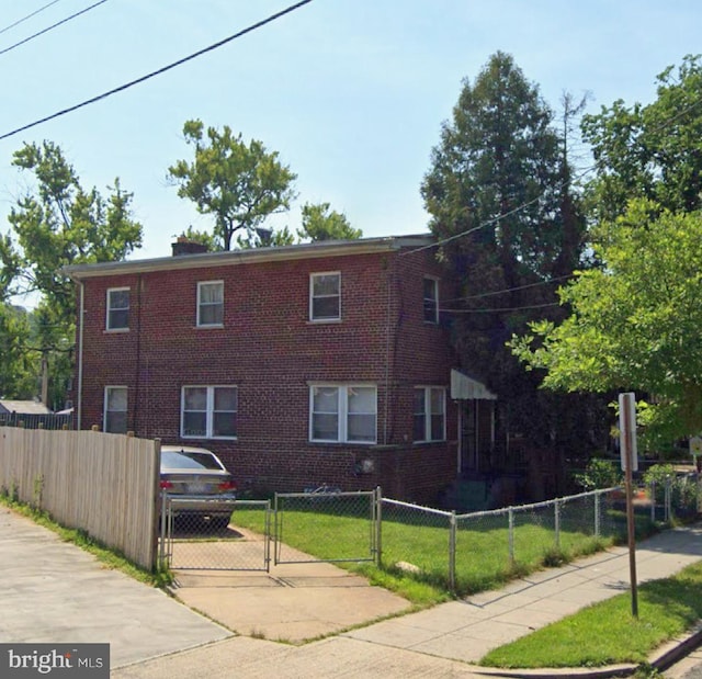 view of front of property with a fenced front yard, a gate, and brick siding