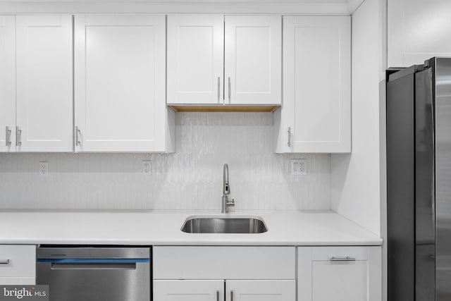 kitchen with white cabinets, stainless steel appliances, a sink, and light countertops