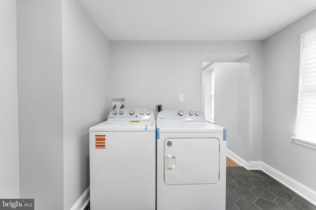 laundry area featuring laundry area, dark tile patterned flooring, washing machine and clothes dryer, and baseboards