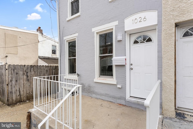 doorway to property with brick siding and fence