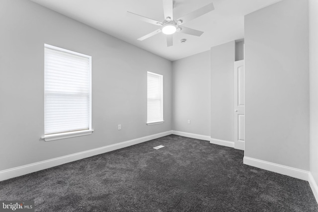 spare room featuring a ceiling fan, dark carpet, and baseboards