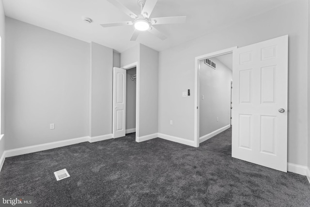 unfurnished bedroom with baseboards, visible vents, dark colored carpet, and a ceiling fan