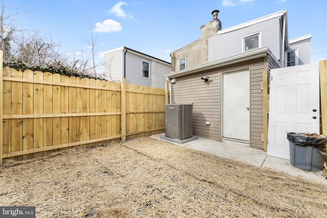 rear view of property featuring central air condition unit and fence