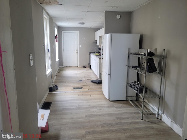 corridor with light hardwood / wood-style floors and a drop ceiling