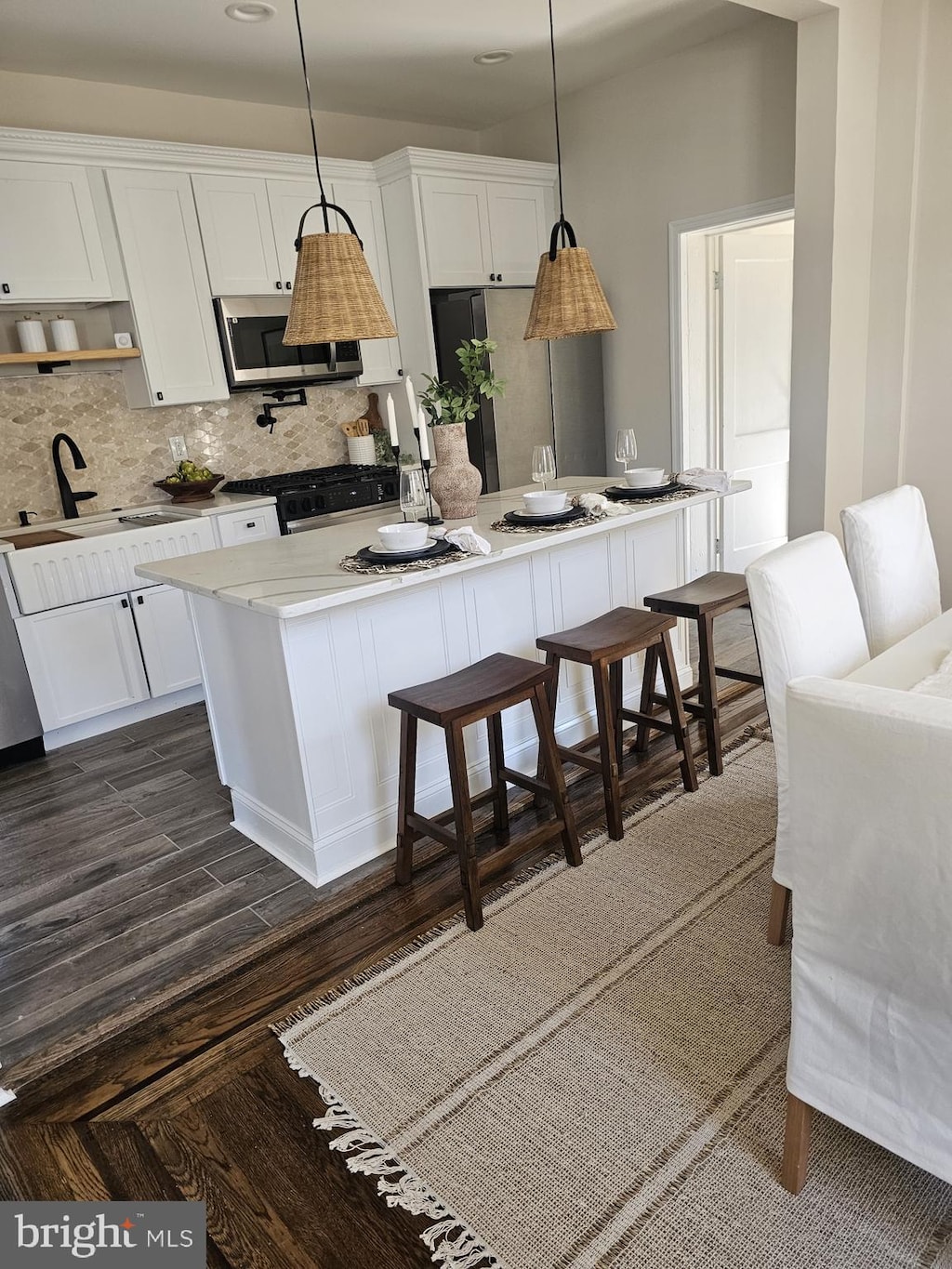 kitchen with decorative backsplash, white cabinets, a kitchen island, and stainless steel appliances