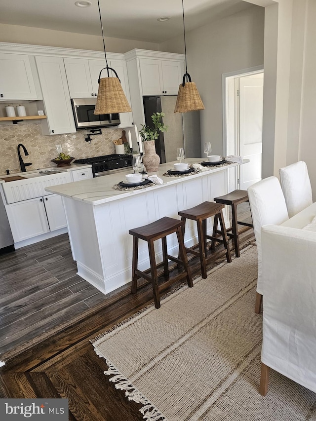 kitchen featuring stainless steel appliances, tasteful backsplash, white cabinets, and a center island