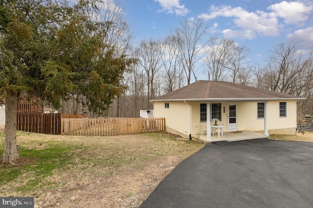 view of property exterior featuring aphalt driveway, a shingled roof, and fence