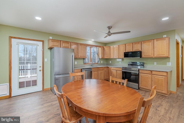 kitchen with a sink, stainless steel appliances, light countertops, and light wood finished floors