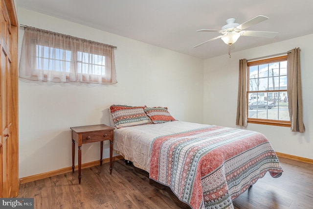 bedroom featuring baseboards, multiple windows, wood finished floors, and a ceiling fan