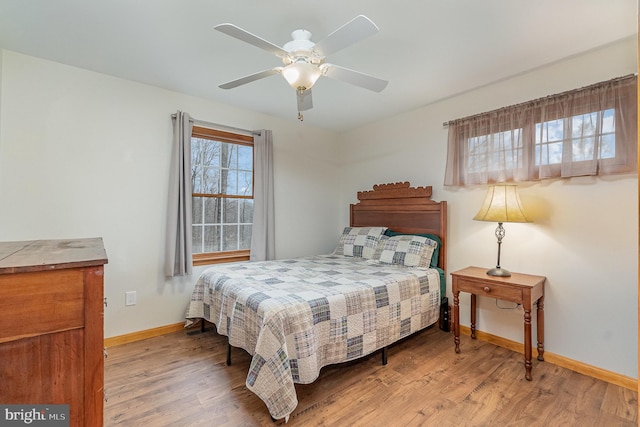 bedroom with a ceiling fan, baseboards, and wood finished floors