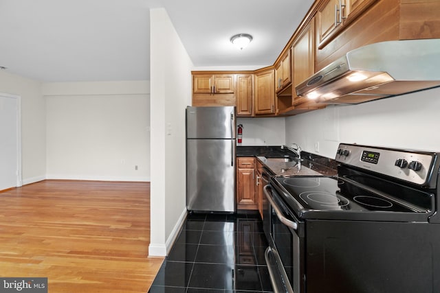 kitchen with sink, stainless steel appliances, dark hardwood / wood-style floors, and dark stone counters